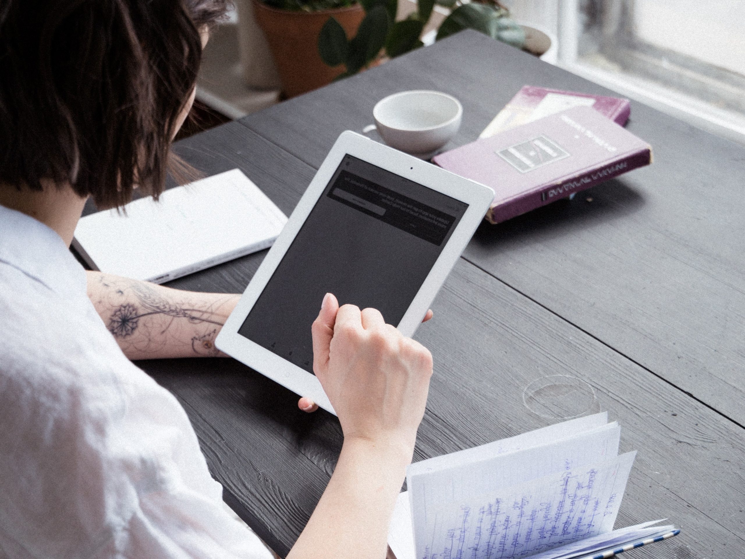 the back of a man holding an iPad, researching about rehab options