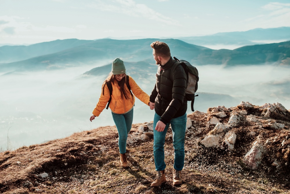 Couple hiking on top of a mountain with fog surrounding them