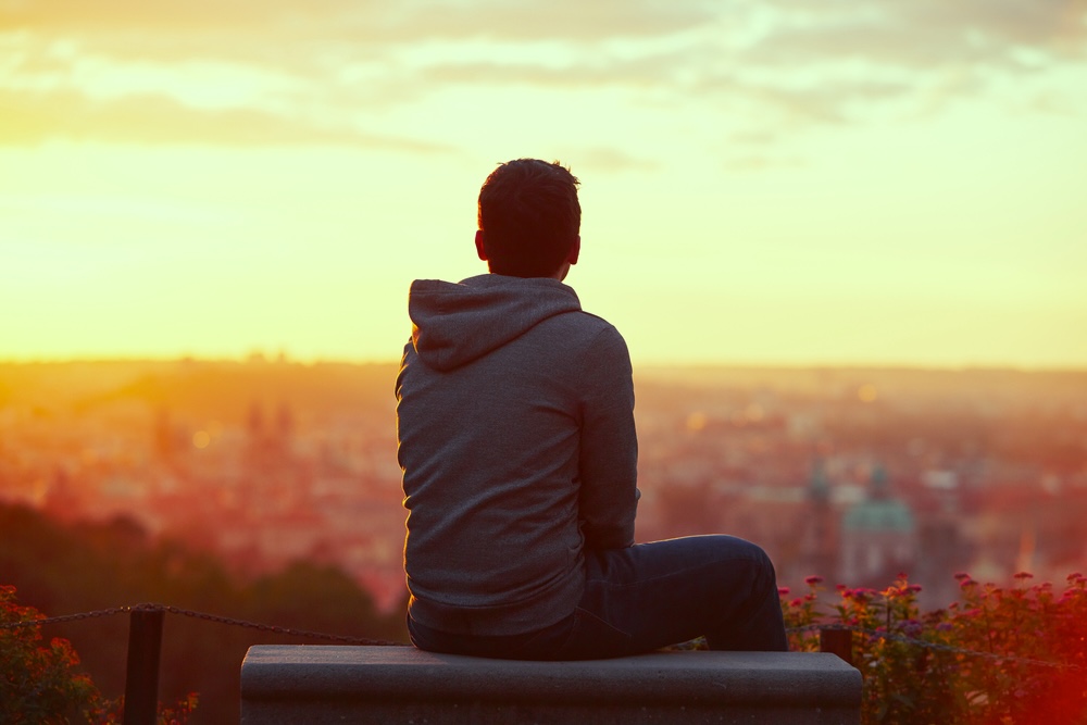 Man sitting on a rooftop looking at sunset views