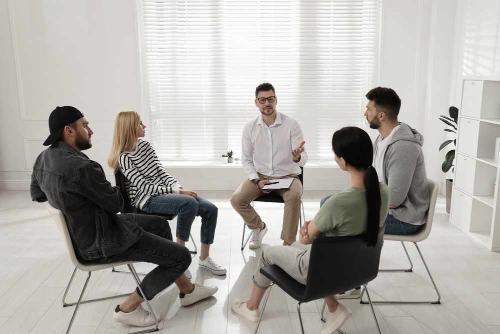 People in recovery living in a sober living home having group recovery meeting post-rehab