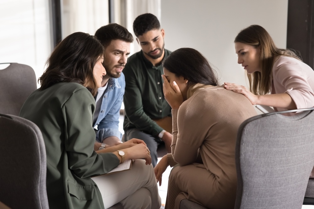 Group comforting a woman while inside rehab